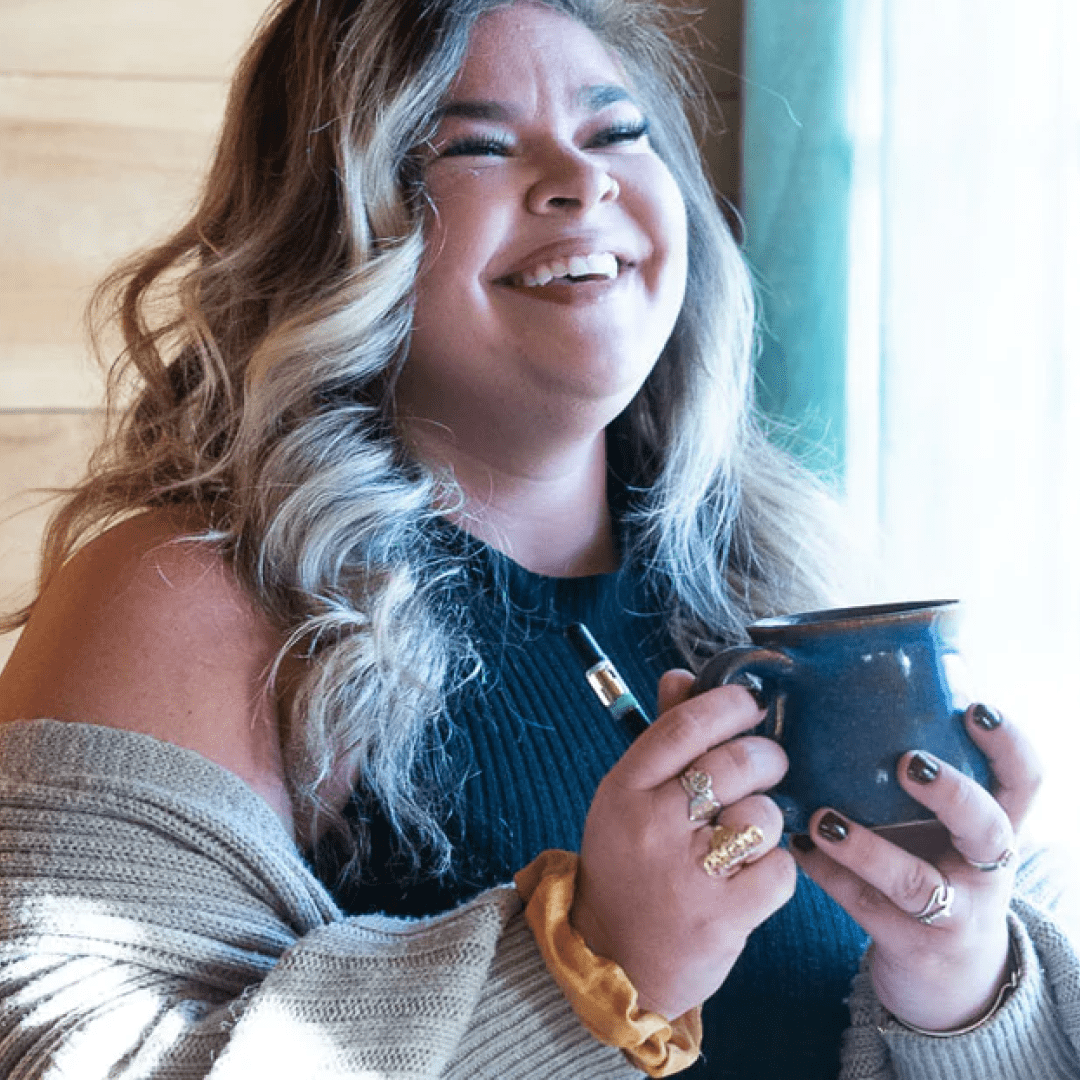 Woman smiling holding a mug and Fernway half gram vape pen
